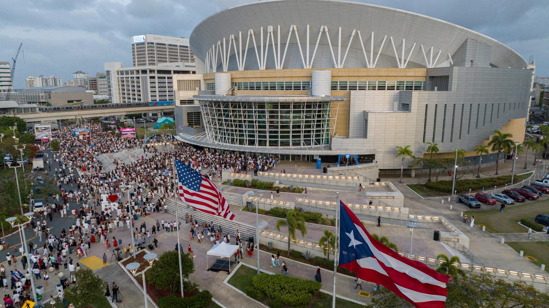 Blick aus der Luft auf das Coliseo in San Juan, davor die Flaggen der USA und Puerto Ricos und klein zu sehen zahlreiche Menschen Blick aus der Luft auf das Coliseo in San Juan, davor die Flaggen der USA und Puerto Ricos und klein zu sehen zahlreiche Menschen