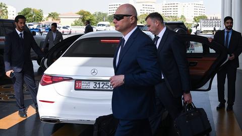 Die russische Delegation verlässt das Hotel in Abu-Dhabi zu Verhandlungen über den Ukraine-Krieg. Mehrere Männer in dunklen Anzügen stehen und gehen um ein weißes Auto herum.