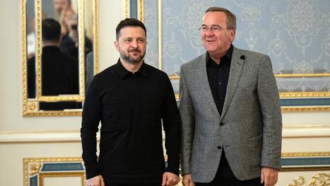 Bundesverteidigungsminister Pistorius und der ukrainische Präsident Selenskyj in Kiew. Beide stehen in einem prachtvollen Raum nebeneinander.