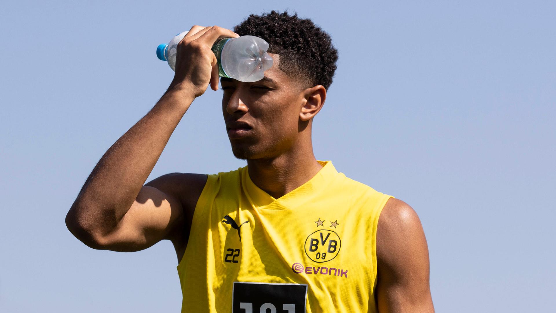 Fußballer Jude Bellingham von Borussia Dortmund kühlt seine Stirn mit einer Wasserflasche.