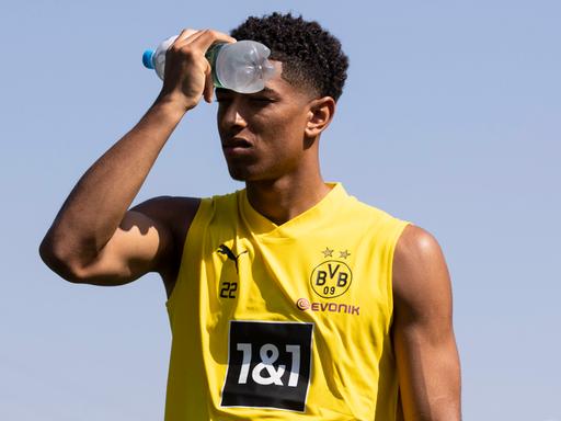 Fußballer Jude Bellingham von Borussia Dortmund kühlt seine Stirn mit einer Wasserflasche.