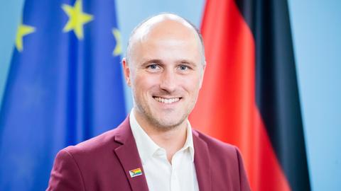 Sven Lehmann steht vor einer europäischen und einer deutschen Fahne