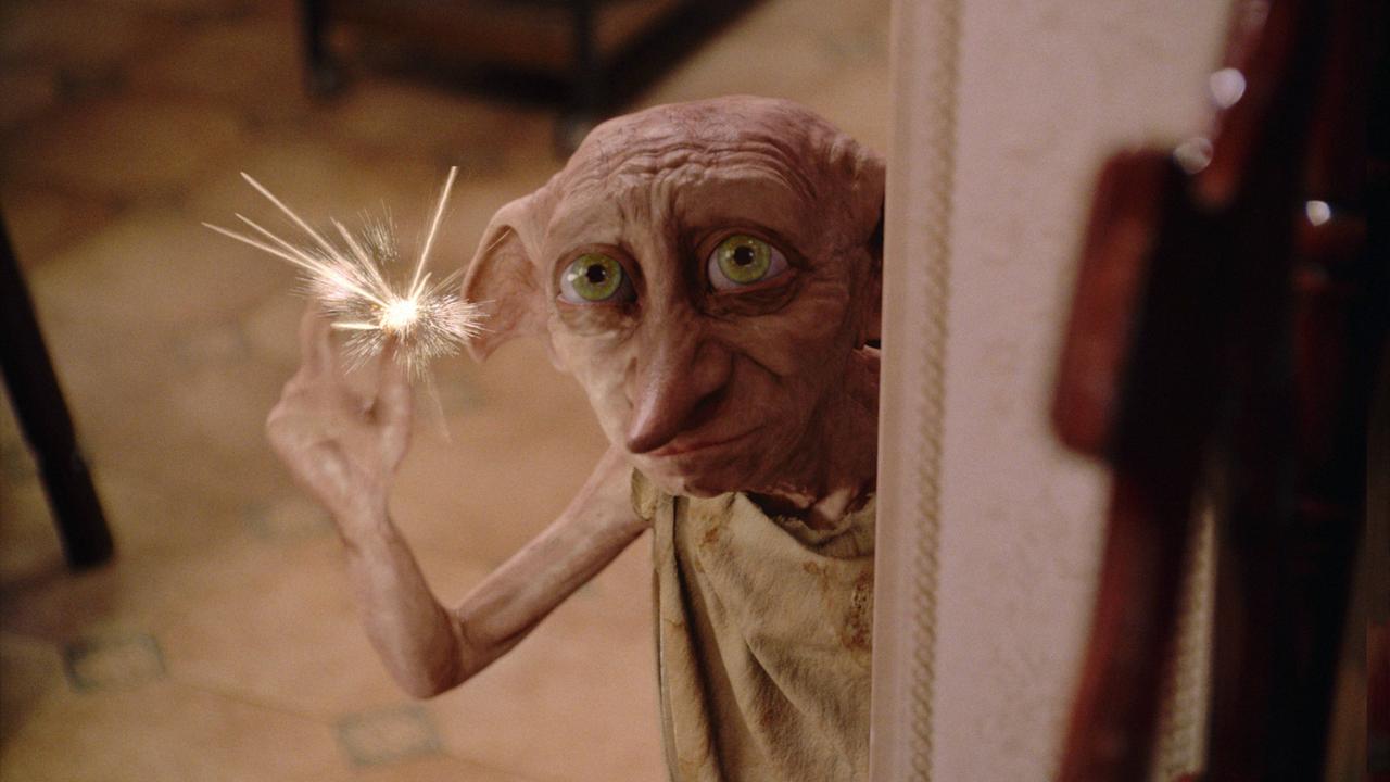 Dobby, der Hauself aus "Harry Potter" hält eine Wunderkerze in der Hand und schaut zerknittert.