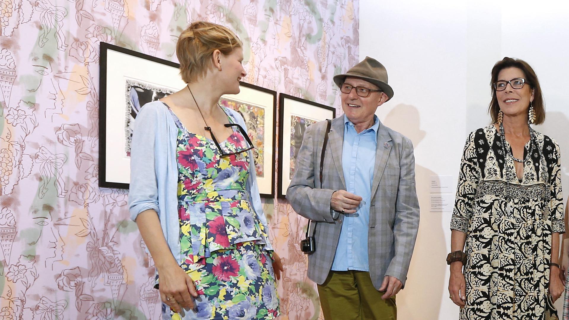 Marc-Camille Chaimowicz steht bei einer Ausstellungseröffnung im New National Museum in Monaco mit Prinzessin Caroline (rechts) und der Künstlerin Laure Prouvost vor einigen Bildern an der Wand Marc-Camille Chaimowicz steht bei einer Ausstellungseröffnung im New National Museum in Monaco mit Prinzessin Caroline (rechts) und der Künstlerin Laure Prouvost vor einigen Bildern an der Wand