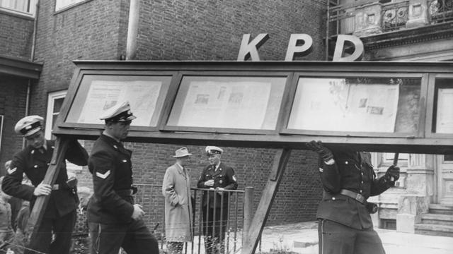 Polizeibeamte tragen 1956 nach dem Verbot eine Hinweiskasten mit den Buchstaben KPD aus den Büroräumen der Partei in Hamburg.