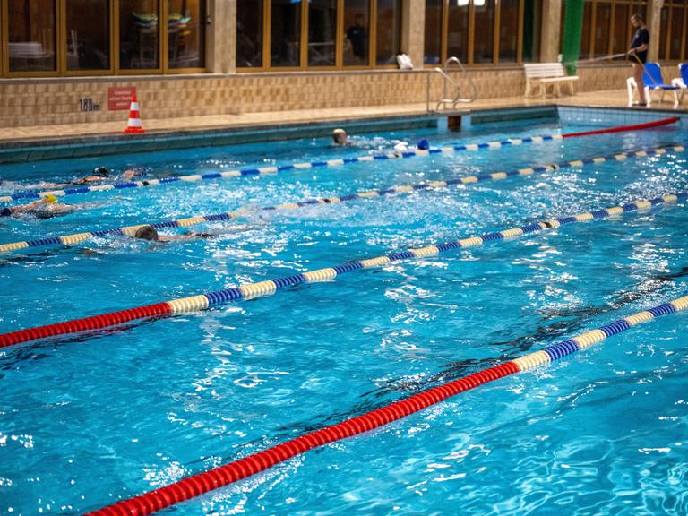 Menschen schwimmen im Wasser in einem Schwimmbad.