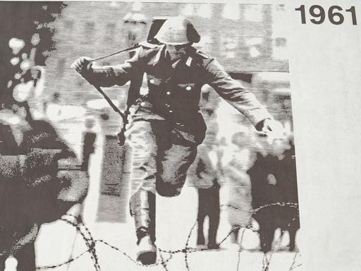 Ein an einem Gebäude aufgeklebtes Foto zeigt, wie ein Soldat im Jahr 1961 über Stacheldraht springt. Ein an einem Gebäude aufgeklebtes Foto zeigt, wie ein Soldat im Jahr 1961 über Stacheldraht springt.