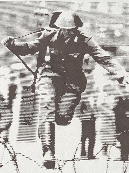 Ein an einem Gebäude aufgeklebtes Foto zeigt, wie ein Soldat im Jahr 1961 über Stacheldraht springt. Ein an einem Gebäude aufgeklebtes Foto zeigt, wie ein Soldat im Jahr 1961 über Stacheldraht springt.