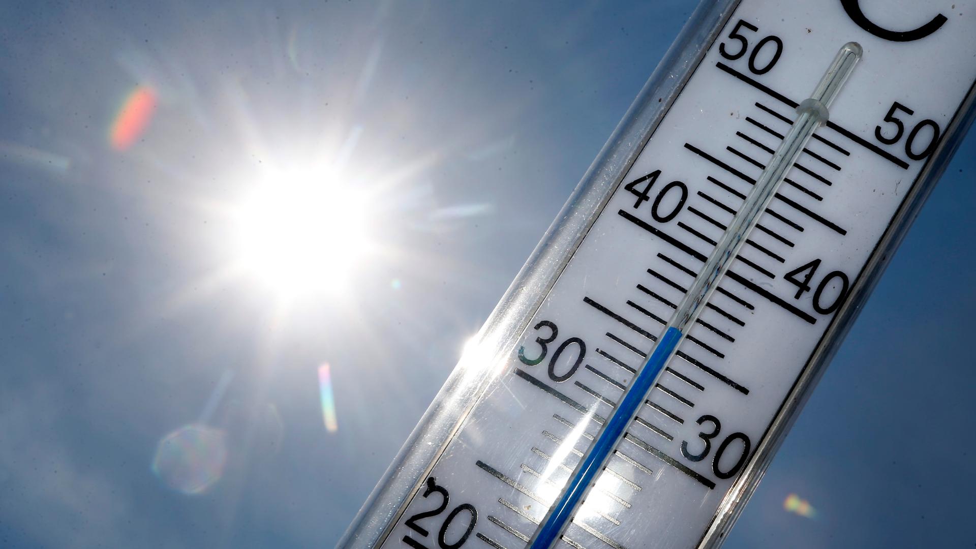 Ein Thermometer zeigt eine Temperatur von 36 Grad. Im Hinter-Grund sieht man die Sonne.