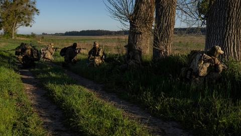 Ukrainische Soldaten auf einem Feldweg mit Gewehren.