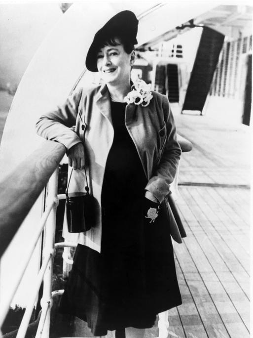 Dorothy Parker steht, an der Reling gelehnt, auf einem Dampfer und lächelt in die Kamera.