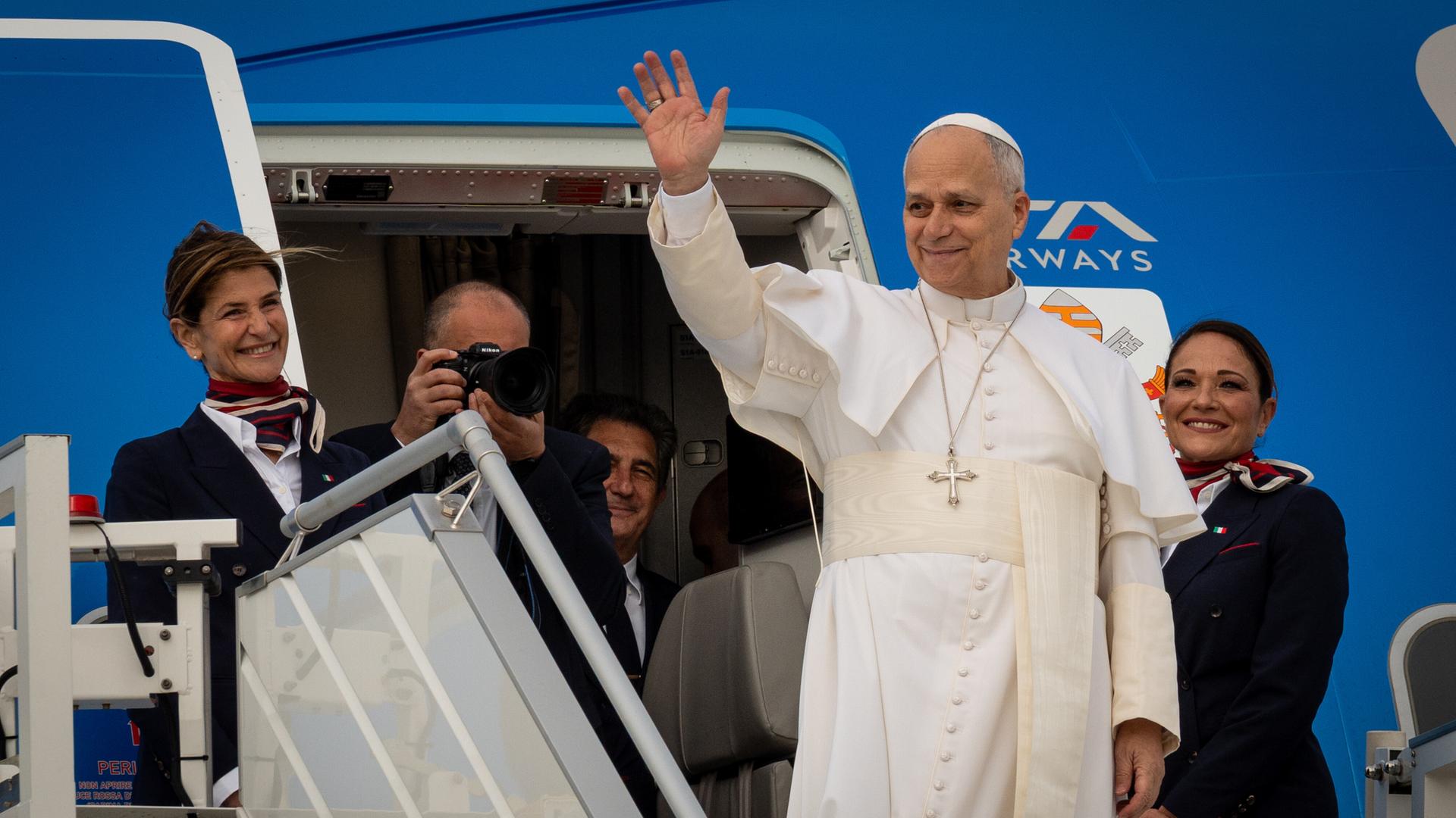 Papst Leo XIV. winkt auf der Treppe eines Flugzeugs. 