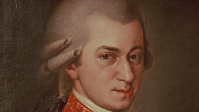 Ein Gemälde zeigt den Komponisten Wolfgang Amadeus Mozart. Er hat eine weiße Perücke auf und schaut streng.