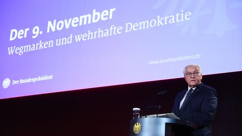 Bundespräsident Steinmeier steht hinter einem Rednerpult. Hinter ihm ist der Slogan "Der 9. November - Wegmarken und wehrhafte Demokratie" zu sehen. 