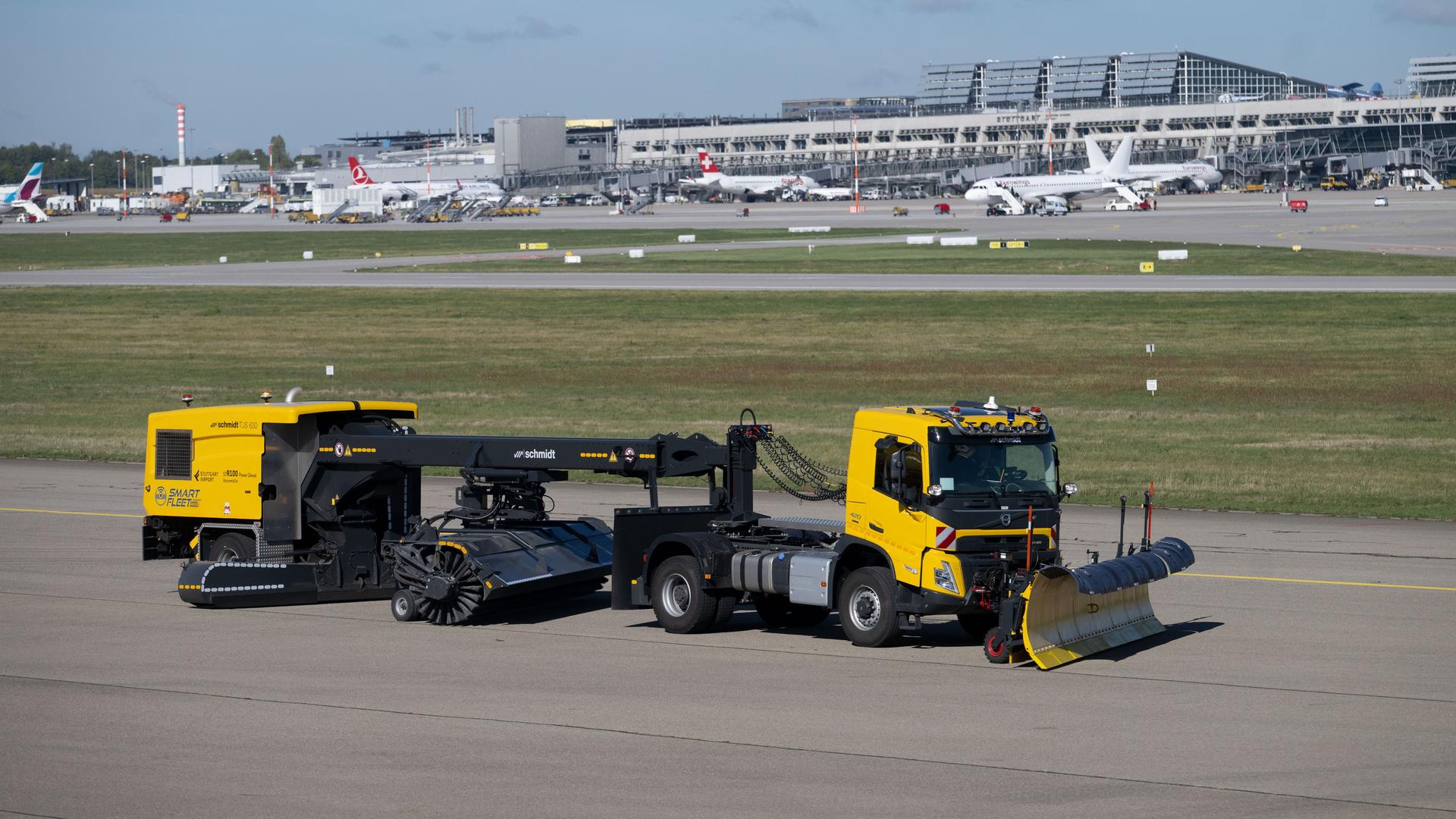 Ein Winterdienstfahrzeug mit autonomen Fahrfunktionen bei einer Vorführfahrt auf dem Vorfeld des Stuttgarter Flughafens. An einem gelben LKW ist vorne eine große Schaufel befestigt. Hinten an dem LKW hängen weitere Module zum Schneeräumen. Ein Winterdienstfahrzeug mit autonomen Fahrfunktionen bei einer Vorführfahrt auf dem Vorfeld des Stuttgarter Flughafens. An einem gelben LKW ist vorne eine große Schaufel befestigt. Hinten an dem LKW hängen weitere Module zum Schneeräumen.