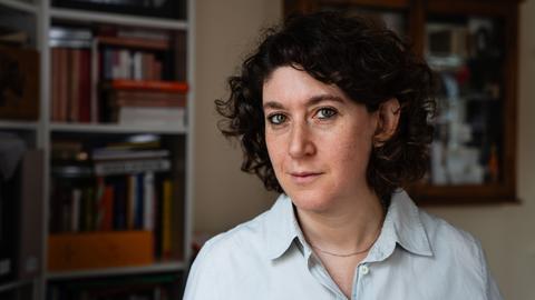 Die Autorin Lena Gorelik blickt in die Kamera, links von ihr ist ein Bücherregal.