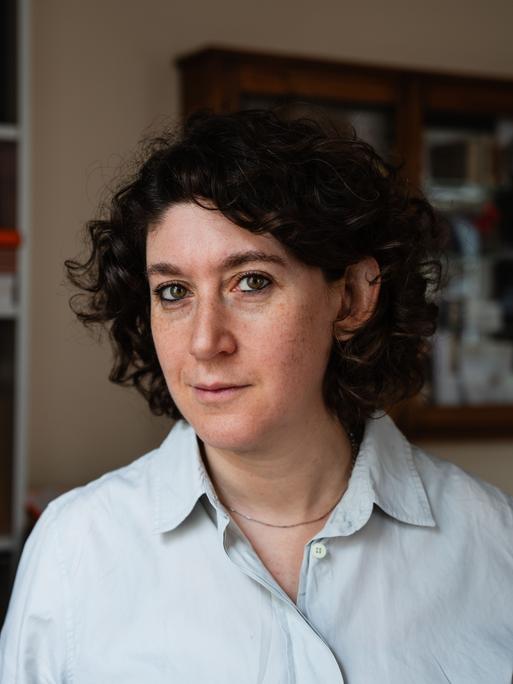 Die Autorin Lena Gorelik blickt in die Kamera, links von ihr ist ein Bücherregal.