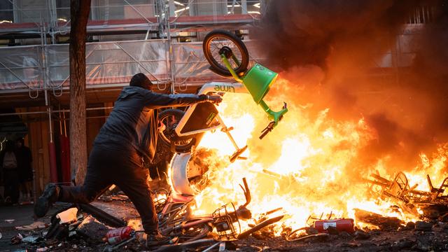 Ein Demonstrant wirft ein Fahrrad in ein Feuer. 