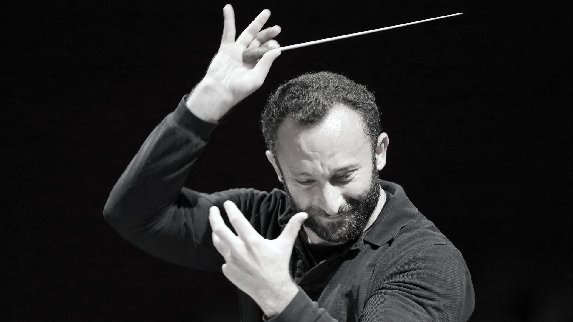 Kirill Petrenko dirigiert mit wilder Geste und einem weißen Stab.