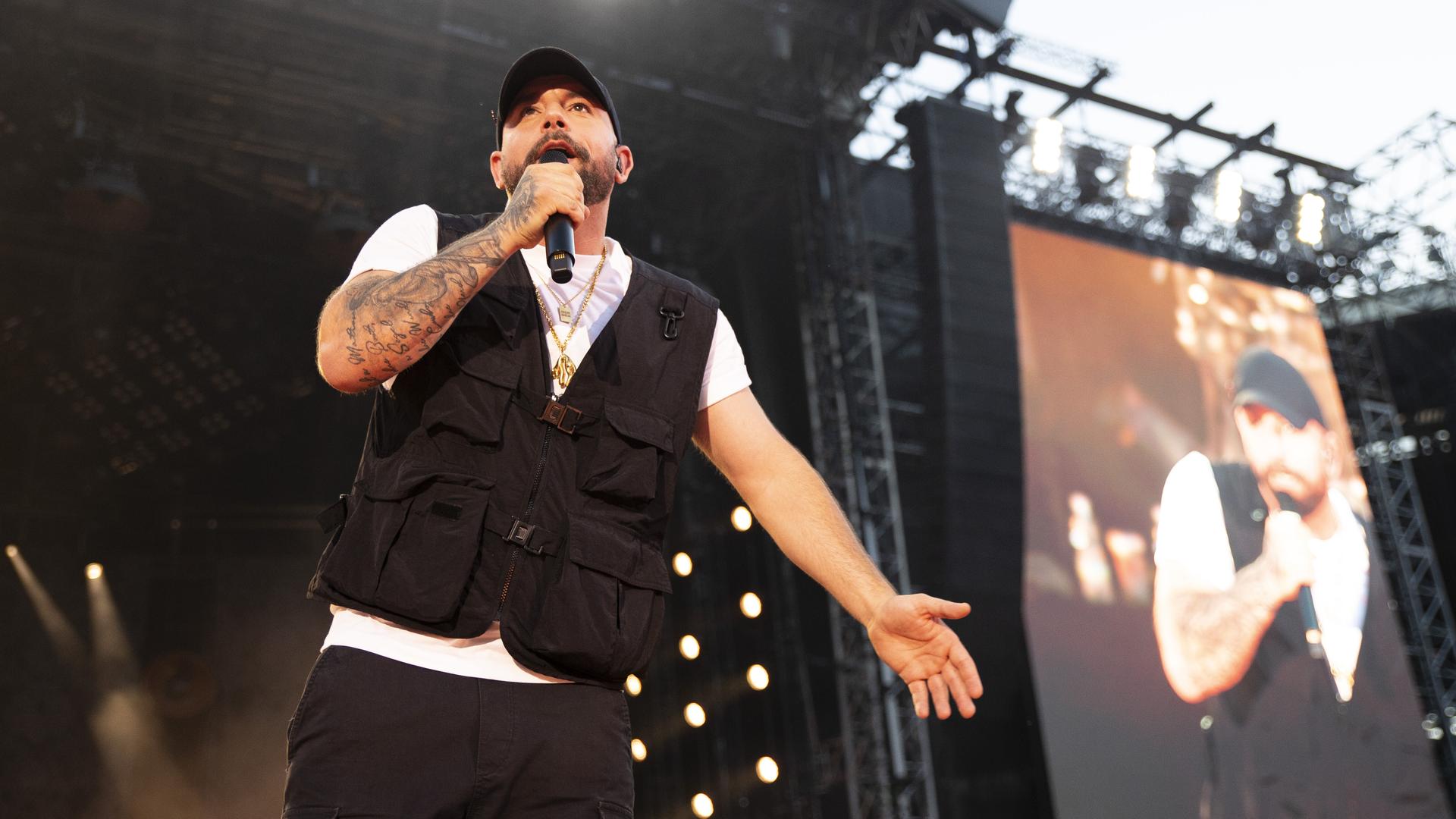 Christopher Seiler steht mit dem Mikro in der Hand auf einer großen Bühne im Ernst-Happel-Stadion in Wien und singt. Christopher Seiler steht mit dem Mikro in der Hand auf einer großen Bühne im Ernst-Happel-Stadion in Wien und singt.