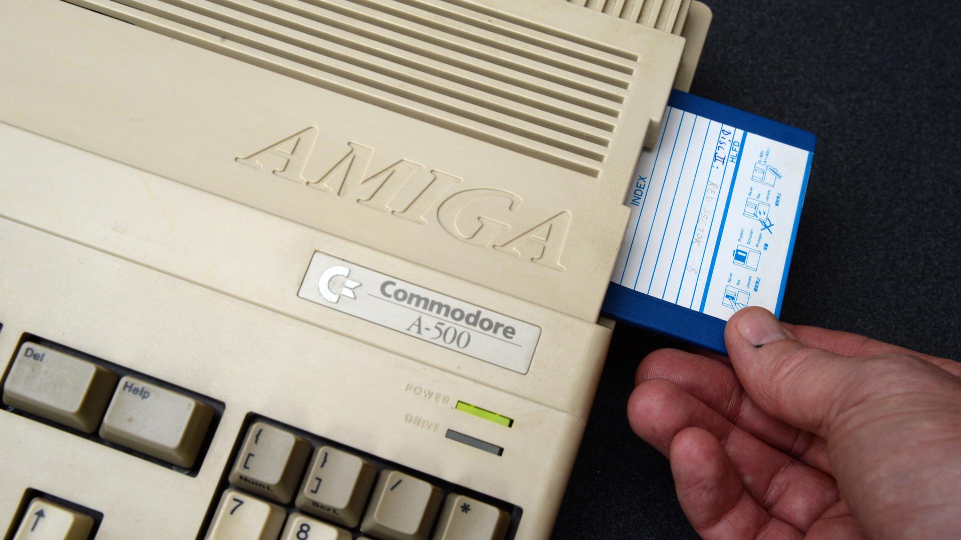 Ein Mann steckt eine Diskette in einen Commodore Amiga 500