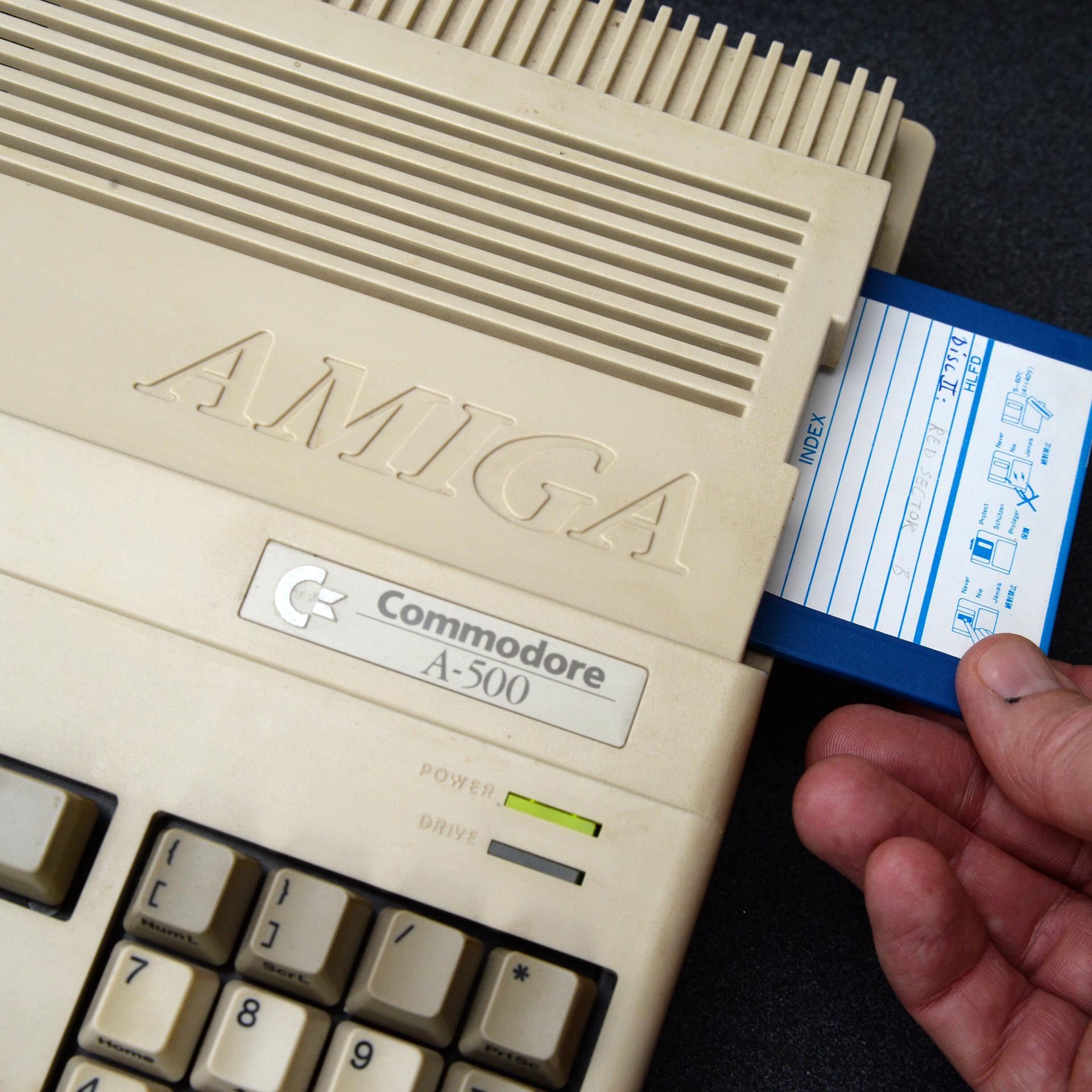 Ein Mann steckt eine Diskette in einen Commodore Amiga 500