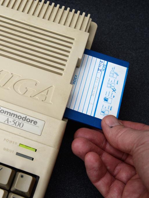 Ein Mann steckt eine Diskette in einen Commodore Amiga 500