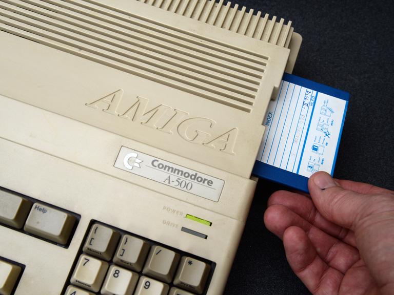 Ein Mann steckt eine Diskette in einen Commodore Amiga 500