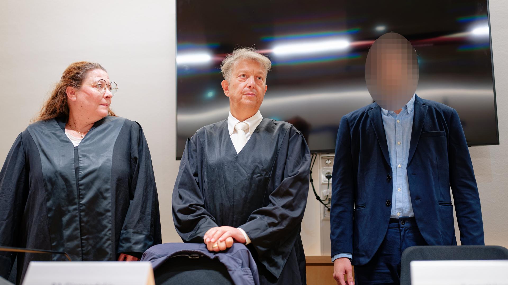 Der Angeklagte steht im Verhandlungs-Saal von dem Land-Gericht neben seinen Rechtsanwälten. Sein Gesicht ist nicht zu erkennen. Der Angeklagte steht im Verhandlungs-Saal von dem Land-Gericht neben seinen Rechtsanwälten. Sein Gesicht ist nicht zu erkennen.