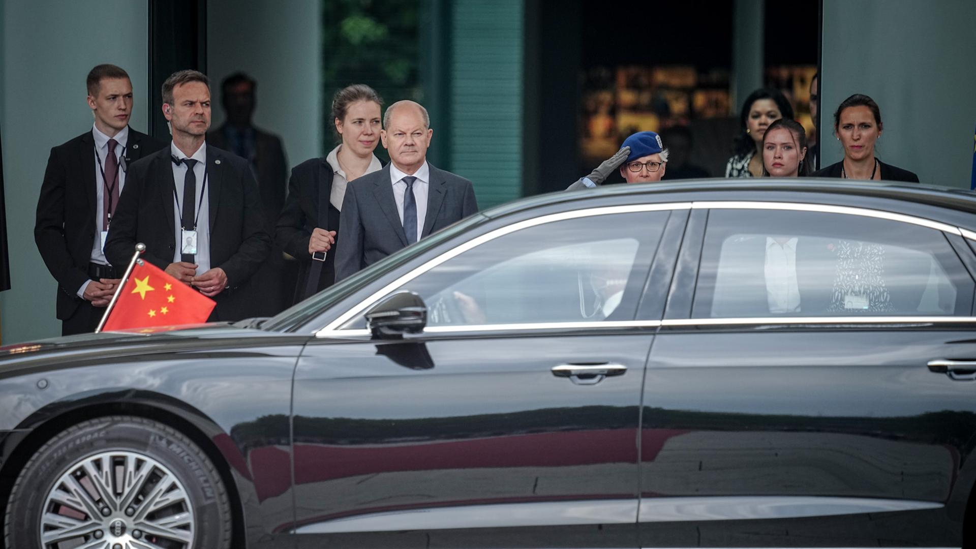 Bundeskanzler Olaf Scholz (SPD, M) wartet auf den chinesischen Ministerpräsidenten Li Qiang, dessen Limousine gerade vorgefahren ist.