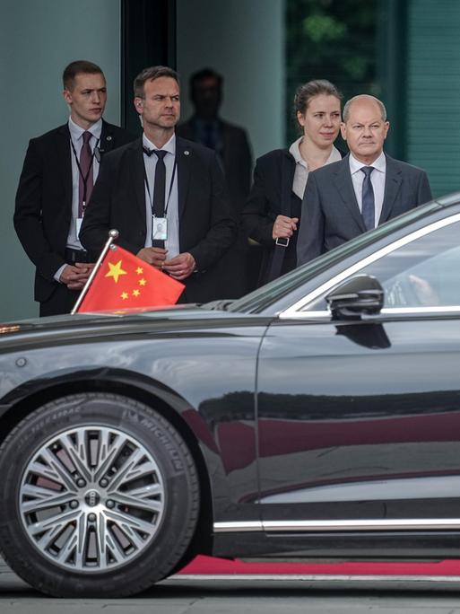 Bundeskanzler Olaf Scholz (SPD, M) wartet auf den chinesischen Ministerpräsidenten Li Qiang, dessen Limousine gerade vorgefahren ist.