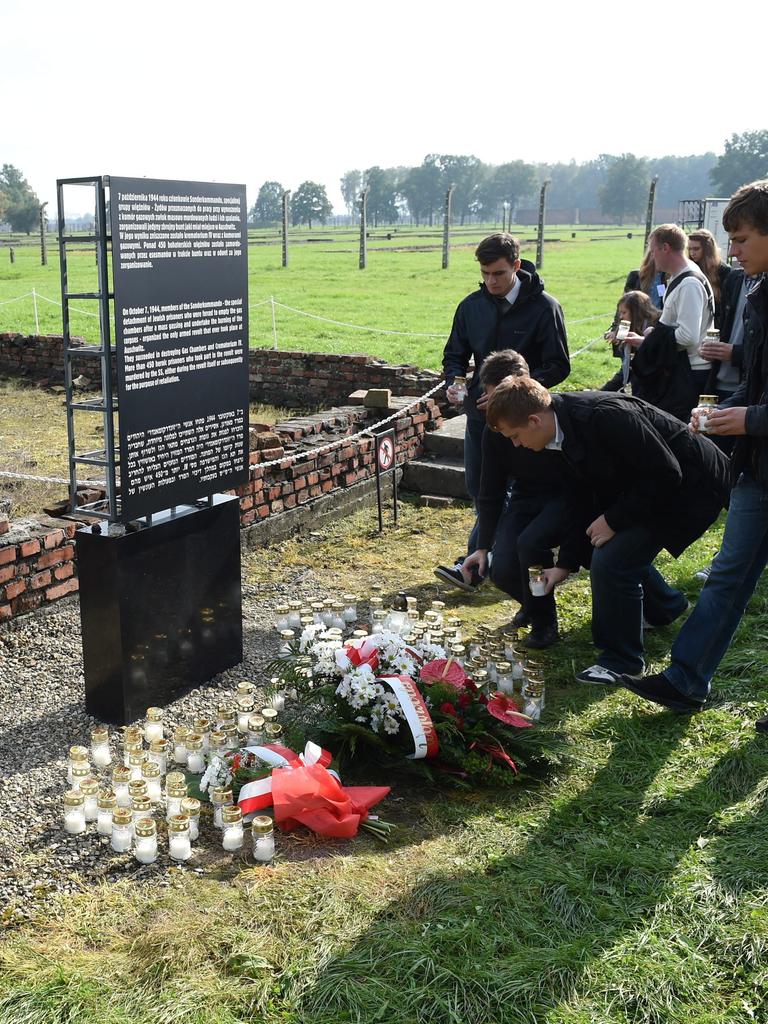 Menschen legen vor einer Gedenktafel im KZ Auschwitz-Birkenau zur Erinnerung an den Aufstand des Sonderkommandos Blumen ab.