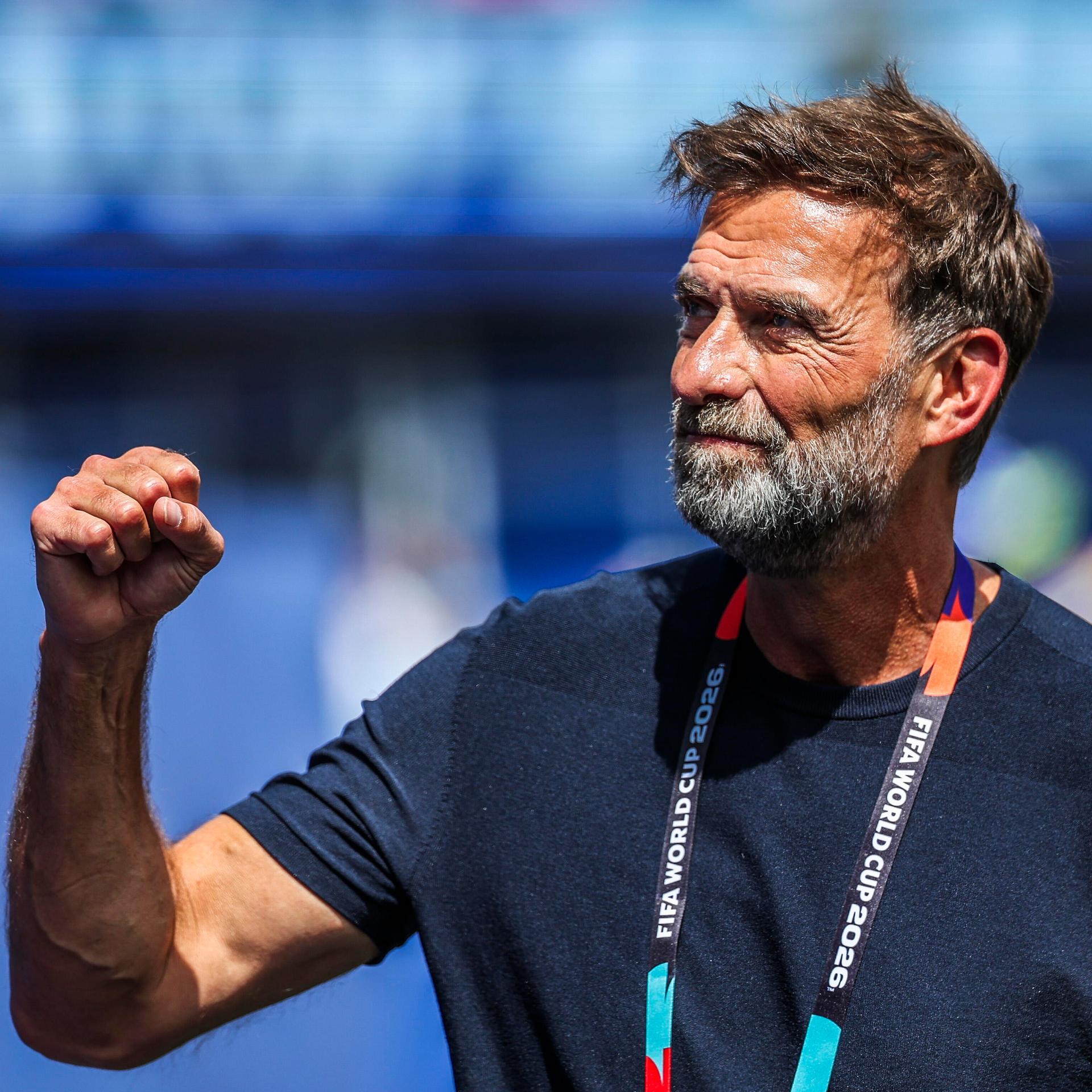 Jürgen Klopp ballt eine Hand zur Faust. Er schaut zur Seite. Er trägt ein dunkelblaues T-Shirt und ein Band zur Fußball-Weltmeisterschaft um den Hals.