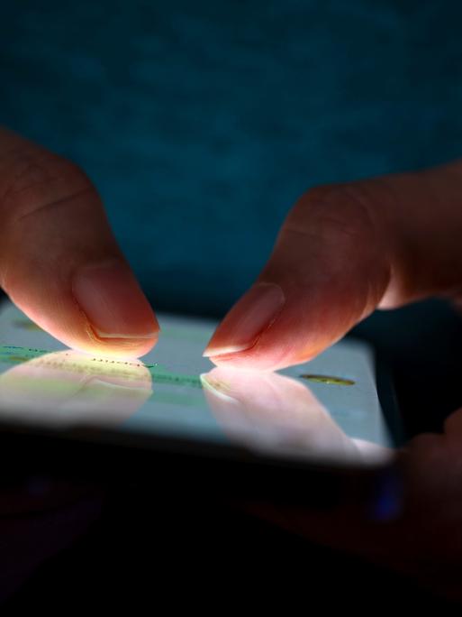 Eine Frau tippt auf ihrem Telefon. Die Beleuchtung hebt die Finger des Benutzers und den Bildschirm des Smartphones hervor. Eine Frau tippt auf ihrem Telefon. Die Beleuchtung hebt die Finger des Benutzers und den Bildschirm des Smartphones hervor.