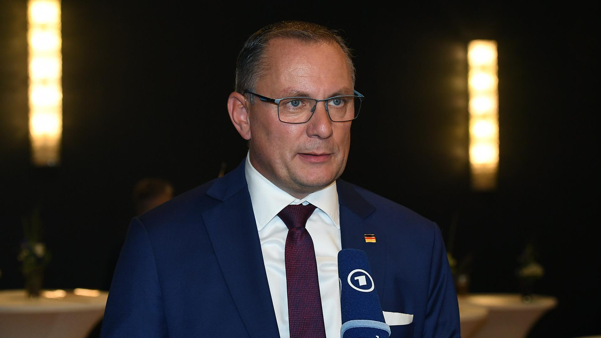 AfD-Chef Tino Chrupalla steht vor einem Mikrofon und spricht. AfD-Chef Tino Chrupalla steht vor einem Mikrofon und spricht.