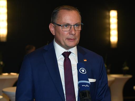 AfD-Chef Tino Chrupalla steht vor einem Mikrofon und spricht. AfD-Chef Tino Chrupalla steht vor einem Mikrofon und spricht.