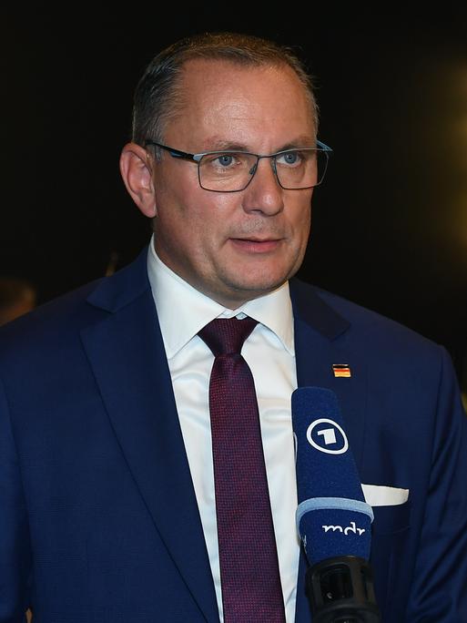 AfD-Chef Tino Chrupalla steht vor einem Mikrofon und spricht. AfD-Chef Tino Chrupalla steht vor einem Mikrofon und spricht.