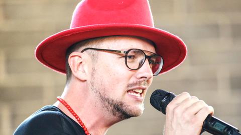 Ees, ein deutschnamibischer Musiker und Musikproduzent und Superstar aus Namibia, mit rotem Hut am Mikrofon. Nahaufname des Gesichts.