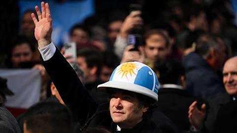 Der argentinische Präsident Javier Milei trägt einen Helm in den Nationalfarben Blau und Weiß.