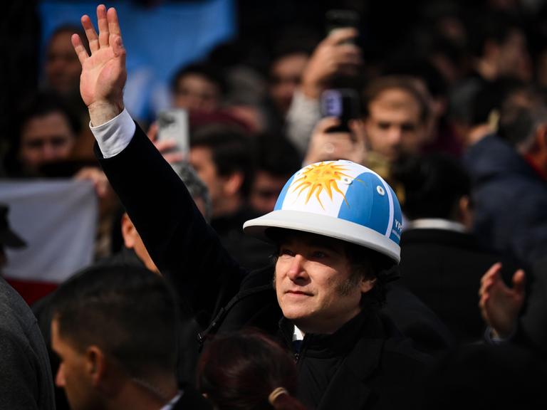 Der argentinische Präsident Javier Milei trägt einen Helm in den Nationalfarben Blau und Weiß.