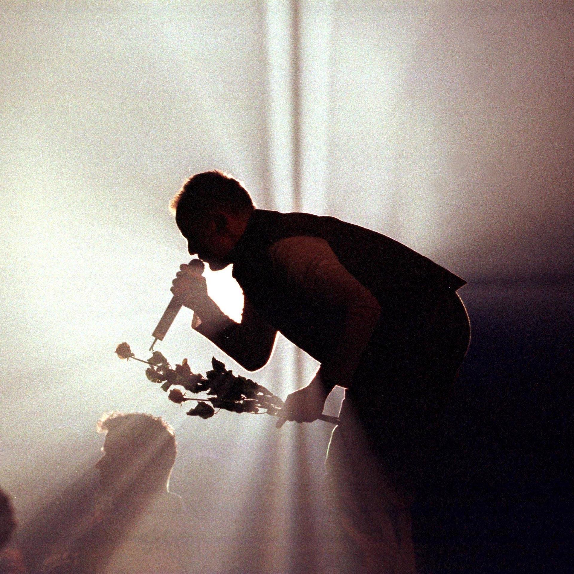 Die Silhouette von Herbert Grönemeyer im grobkörnigen Gegenlicht eines Scheinwerfers während eines Konzerts zum Zeitpunkt seines Albums Mensch.