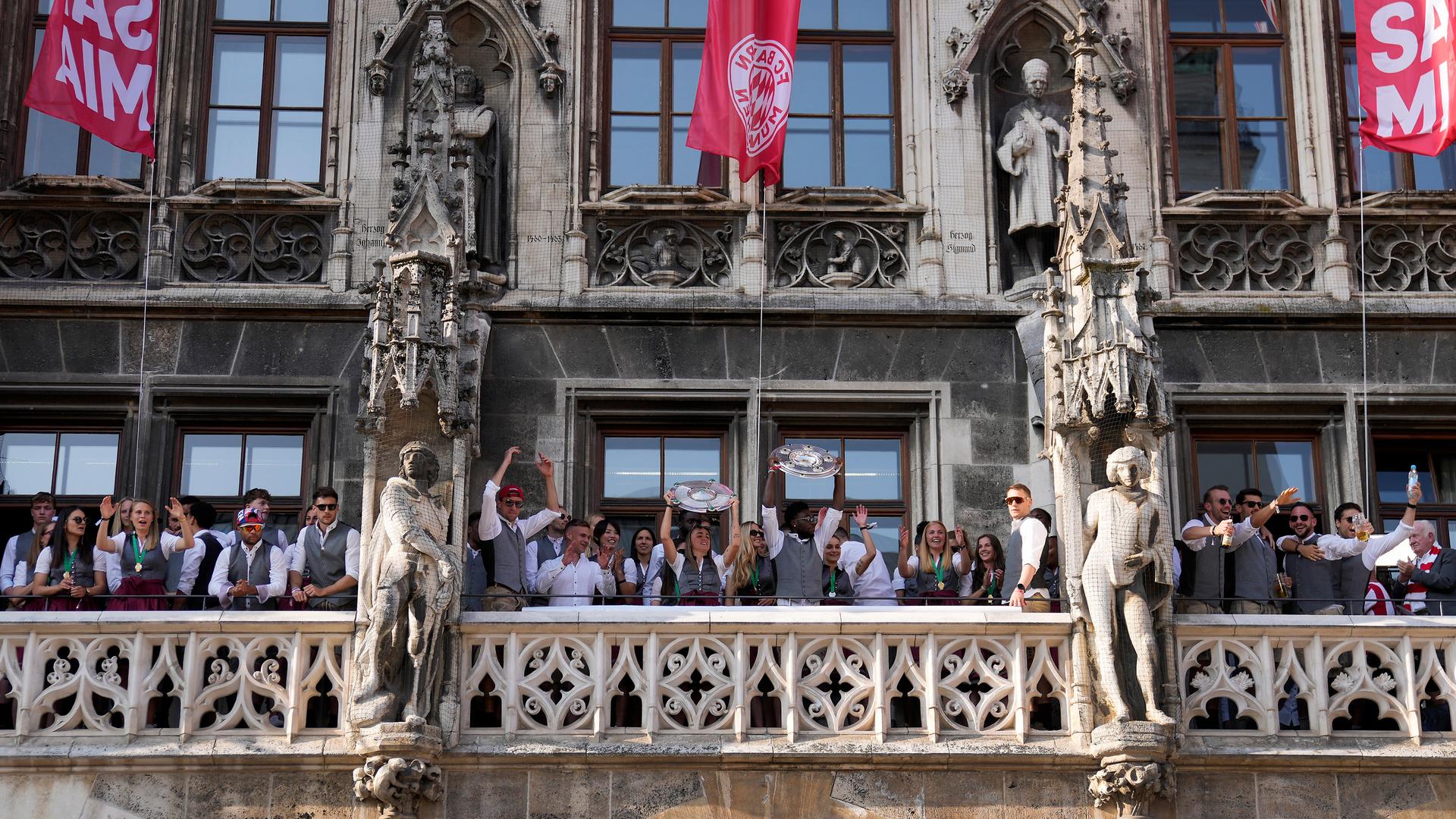 Spielerinnen und Spieler von Bayern München stehen auf dem Rathaus-Balkon und feiern. 