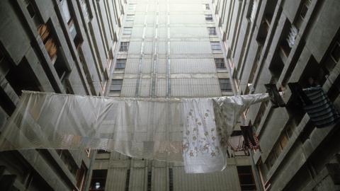 Historische analoge Farbfotografie: Wäsche hängt zum Trocknen auf der Leine zwischen Plattenbautfassaden im Belgrad Ende der 80er Jahre. Es ist kein Horizont zu sehen, aber es scheint ein fahles Licht von oben auf den Beton 