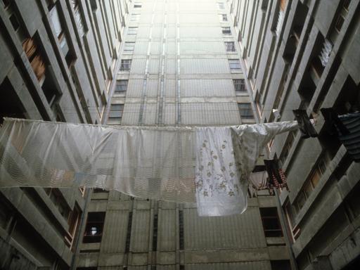 Historische analoge Farbfotografie: Wäsche hängt zum Trocknen auf der Leine zwischen Plattenbautfassaden im Belgrad Ende der 80er Jahre. Es ist kein Horizont zu sehen, aber es scheint ein fahles Licht von oben auf den Beton 