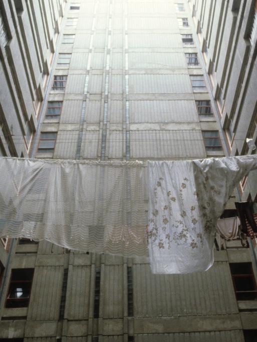 Historische analoge Farbfotografie: Wäsche hängt zum Trocknen auf der Leine zwischen Plattenbautfassaden im Belgrad Ende der 80er Jahre. Es ist kein Horizont zu sehen, aber es scheint ein fahles Licht von oben auf den Beton 