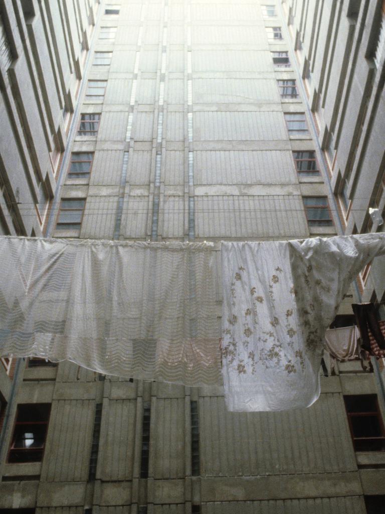 Historische analoge Farbfotografie: Wäsche hängt zum Trocknen auf der Leine zwischen Plattenbautfassaden im Belgrad Ende der 80er Jahre. Es ist kein Horizont zu sehen, aber es scheint ein fahles Licht von oben auf den Beton 