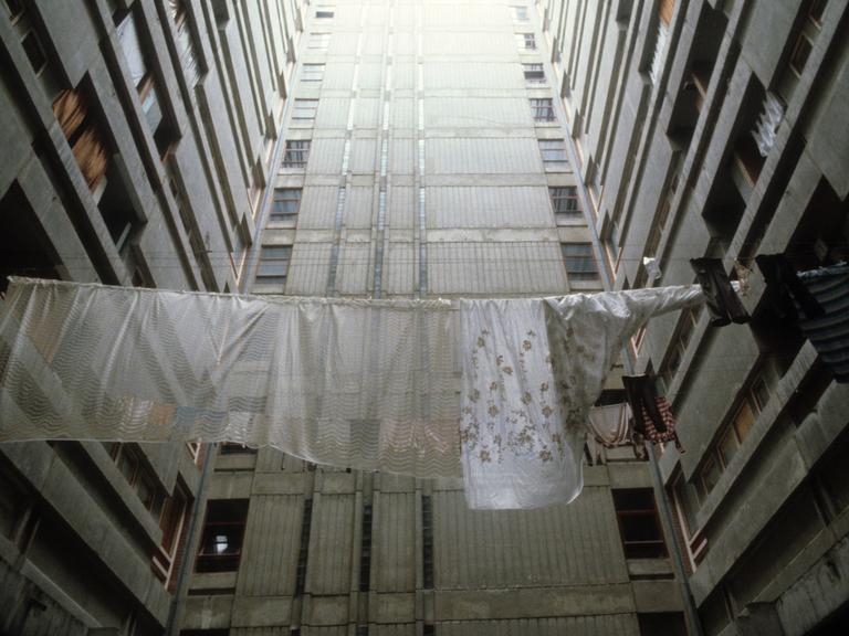 Historische analoge Farbfotografie: Wäsche hängt zum Trocknen auf der Leine zwischen Plattenbautfassaden im Belgrad Ende der 80er Jahre. Es ist kein Horizont zu sehen, aber es scheint ein fahles Licht von oben auf den Beton 