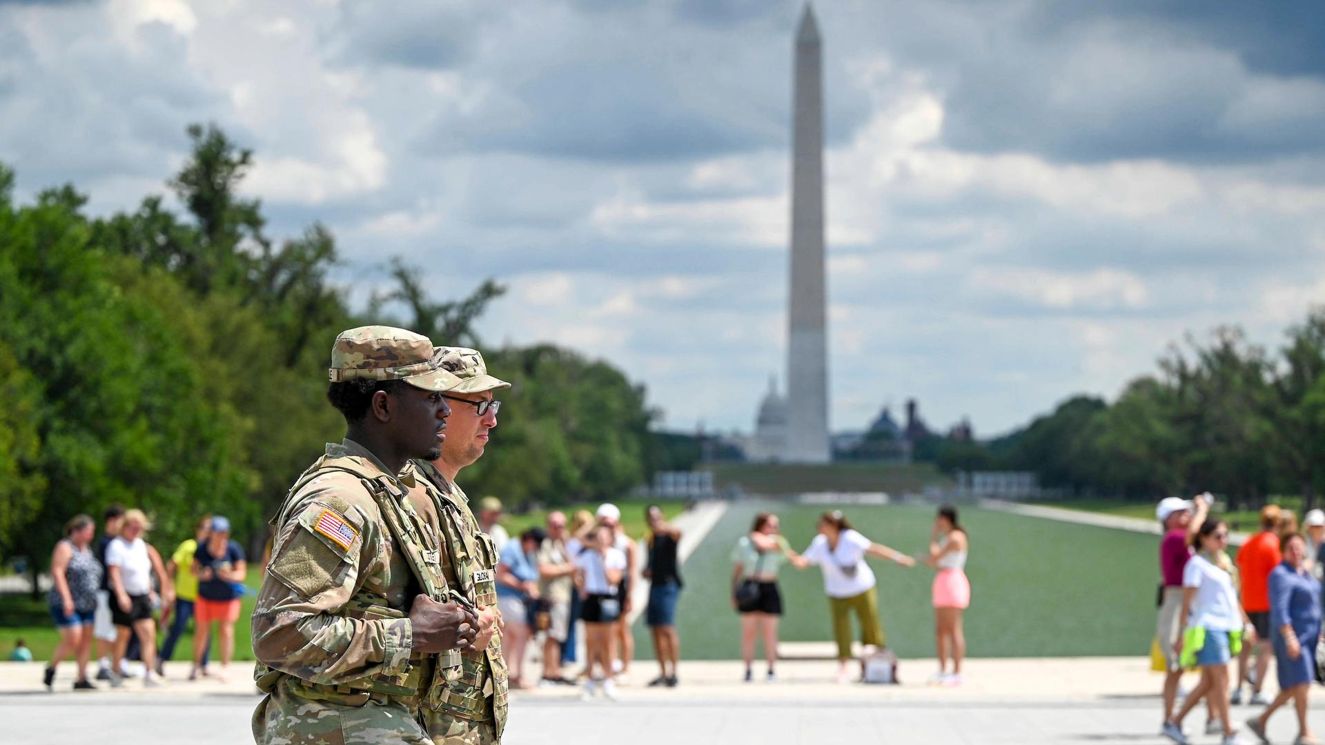 In Washington patroullieren zwei Soldaten der Nationalgarde entlang der National Mall, im Hintergrund sind Touristen zu sehen und das Washington Monument.