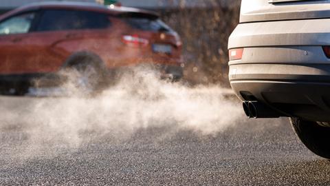 Helle Abgase kommen aus dem Auspuff eines silbergrauen Autos.