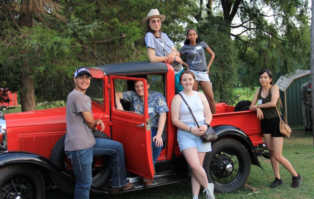 Jugendliche vom American Exchange Project mit einem roten Auto auf Tour in Texas